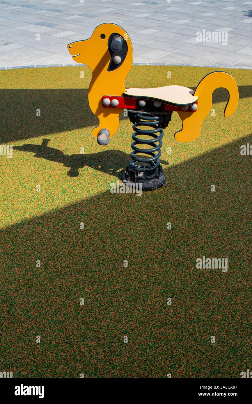 Un cavaliere a forma di cane (Spring rocker) in un parco giochi pubblico, giochi d'infanzia, simbolico Foto Stock