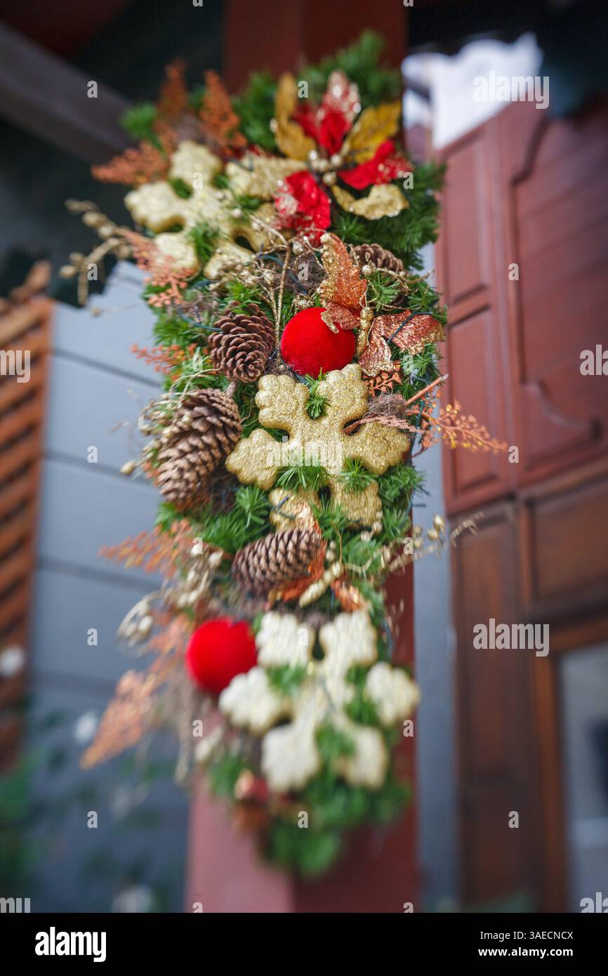 Una corona decorativa natalizia è appesa su una parete con palle di natale, stelle e coni di pino. Foto Stock
