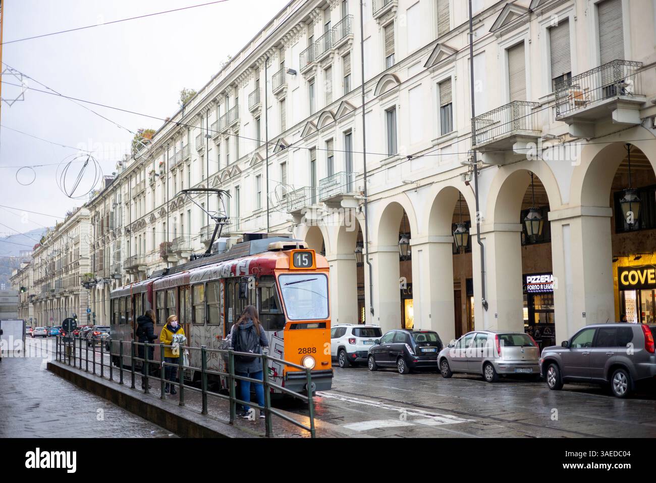 Torino, Italia - 08 novembre 2021: Tram e auto parcheggiate lungo una strada con passaggi ad arco davanti agli edifici Foto Stock