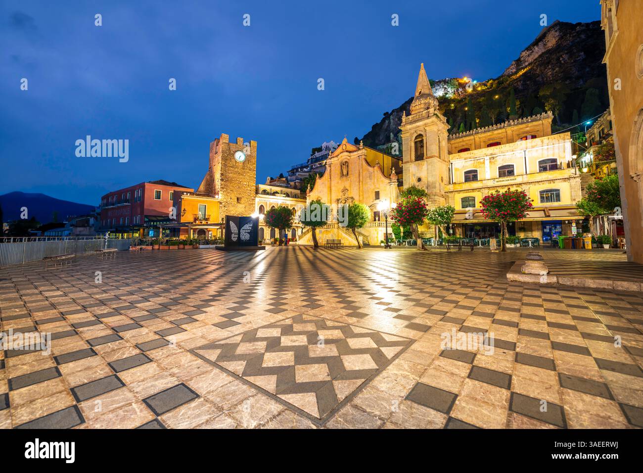 Taormina Piazza IX aprile, 9 aprile panoramica. Piazza piastrellata, torre dell'orologio e chiesa in Sicilia, Italia. Taormina al tramonto, nessuna gente. Foto Stock