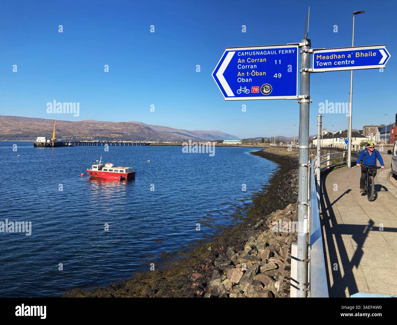 Ciclista sul lungomare e barche da pesca a Loch Linnhe, Fort William, Scozia - Immagine stock catturata con smartphone
