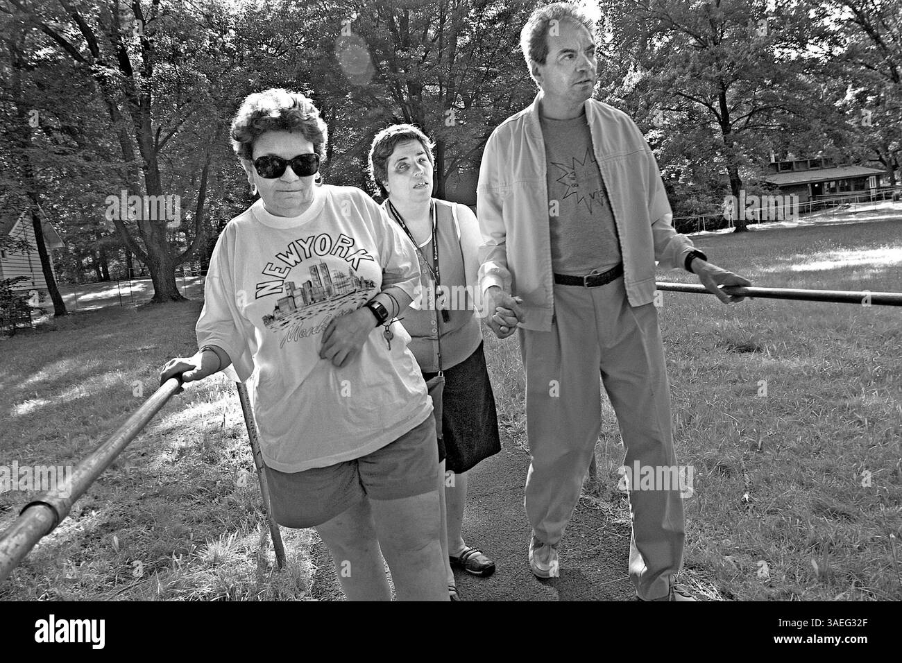 15 luglio 2004; Spring Valley, New York, Stati Uniti; VALERIE BERKOWIZ, GAIL PETRAGLIA e CARLOS JORGE utilizzano il sistema ferroviario del campo per raggiungere a piedi le lezioni di recitazione e computer. Nascosto tra le colline di Spring Valley, New York, è un campo estivo per i non vedenti. I suoi trentacinque ettari di verde sono di solito pieni di bambini, ma per due settimane di mezza estate gli adulti ciechi buttano fuori i bambini ciechi e si impadroniscono del campo da soli. YouÕd lo sa a malapena, però, perché i campeggiatori adulti, molti tra i 70 e i 80 anni, si comportano proprio come bambini. Gettano via le canne bianche, tolgono i loro cani guida al guinzaglio, cantano bawd Foto Stock