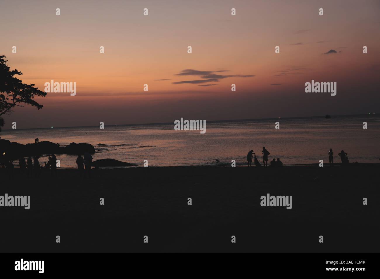 Un tranquillo e bellissimo tramonto sulla spiaggia con splendide sagome di persone riunite Foto Stock