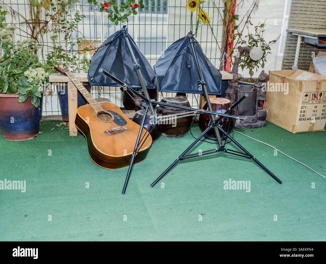 Gunsan, Corea del Sud, 3 novembre 2020: Chitarra in legno e luci di scena appoggiate contro la panchina sul palco verde a Gyeongamdong Railroad Town, Asia Foto Stock
