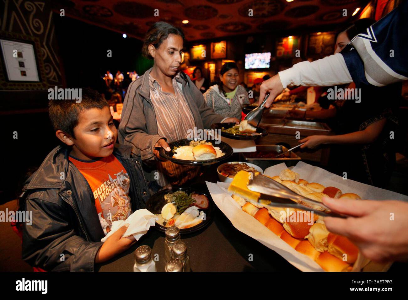 24 novembre 2011 - San Diego, CA, USA - 24 novembre 2011 San Diego, CA, USA. | Maria Ruiz, centro, e il figlio Martin, 8 anni, insieme a Maria Isabella, 10 anni, destra, riempirono i loro piatti alla festa del Ringraziamento nella Casa dei Blues. Attraverso una collaborazione con Feeding America e il San Diego Unified School District, la House of Blues ha ospitato un pasto per circa 700 persone il giovedì. Con l'intrattenimento della Mission Bay High jazz band, un coro gospel e alcuni altri artisti, un gruppo selezionato di bambini delle scuole locali e le loro famiglie hanno festeggiato con la tradizionale tariffa del Ringraziamento della turchia, Mashed p Foto Stock