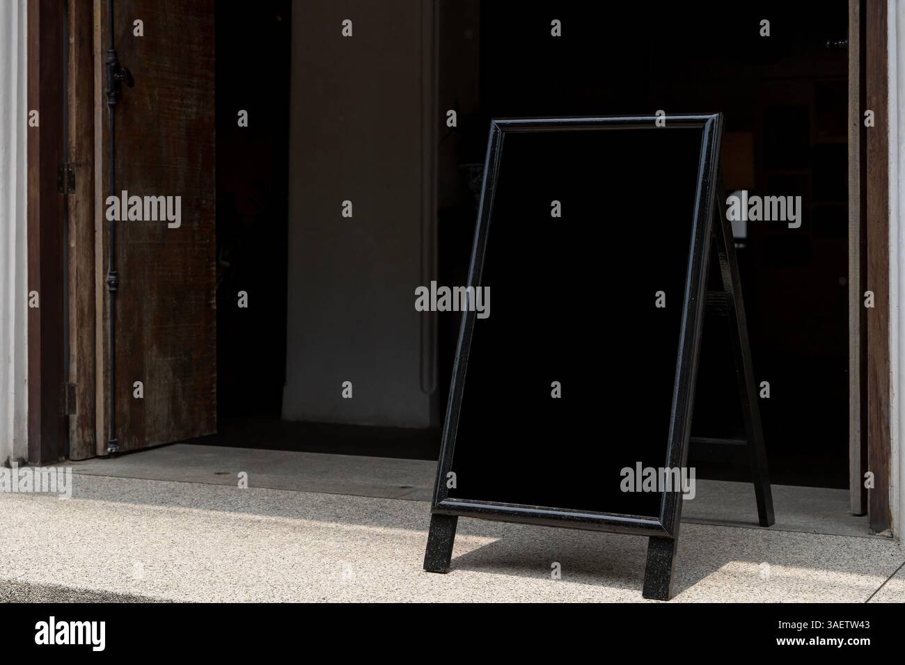 Cartello per pannelli sandwich nero vuoto marciapiede stucco bianco parete poster naturale superficie pulita estetica minimalista tabellone per affissioni luce solare ombra cemento nero Foto Stock