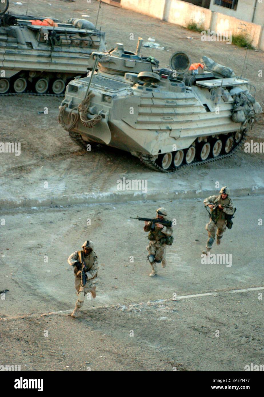 20 novembre 2004; Fallujah, Iraq; tre Marines del 3° plotone, compagnia C, 1/3 scendono dal loro veicolo d'assalto anfibio per entrare in un complesso che hanno preso fuoco la notte prima. Foto Stock