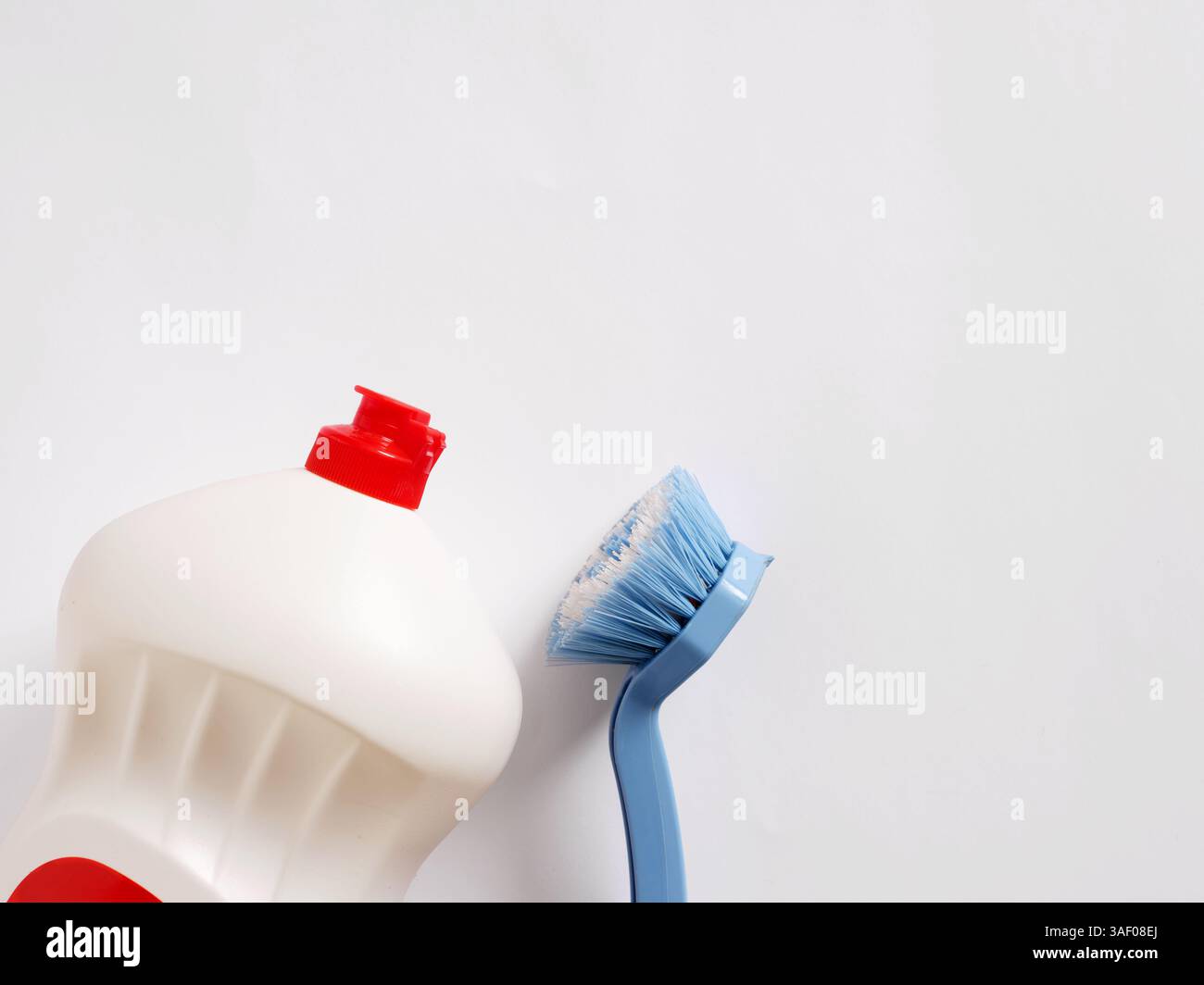 Spazzola per piatti blu e flacone bianco con detergente per tappo rosso su sfondo bianco con spazio di copia Foto Stock