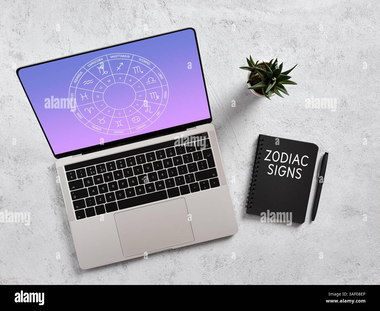 Studiare astrologia su un computer portatile, con un notebook e una penna sulla scrivania, esplorare i segni zodiacali e gli oroscopi Foto Stock