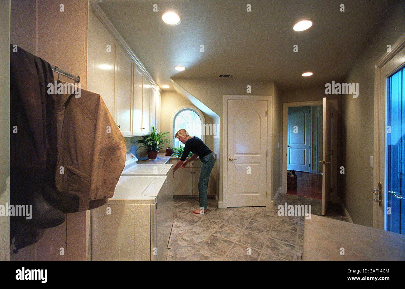 Tracey Buck-Walsh bagna alcune piante nel lavandino del fango/lavanderia. L'attrezzatura da caccia dell'anatra di marito Danny è appesa a sinistra e l'ingresso alla parte principale della casa è dritto, con la porta verso il patio sulla destra e la porta verso il garage è dietro la telecamera. 11.9.00 Vedi mcdade Cal Life story Sacramento Bee foto di Owen Brewr ID998 /ZUMA Press Foto Stock