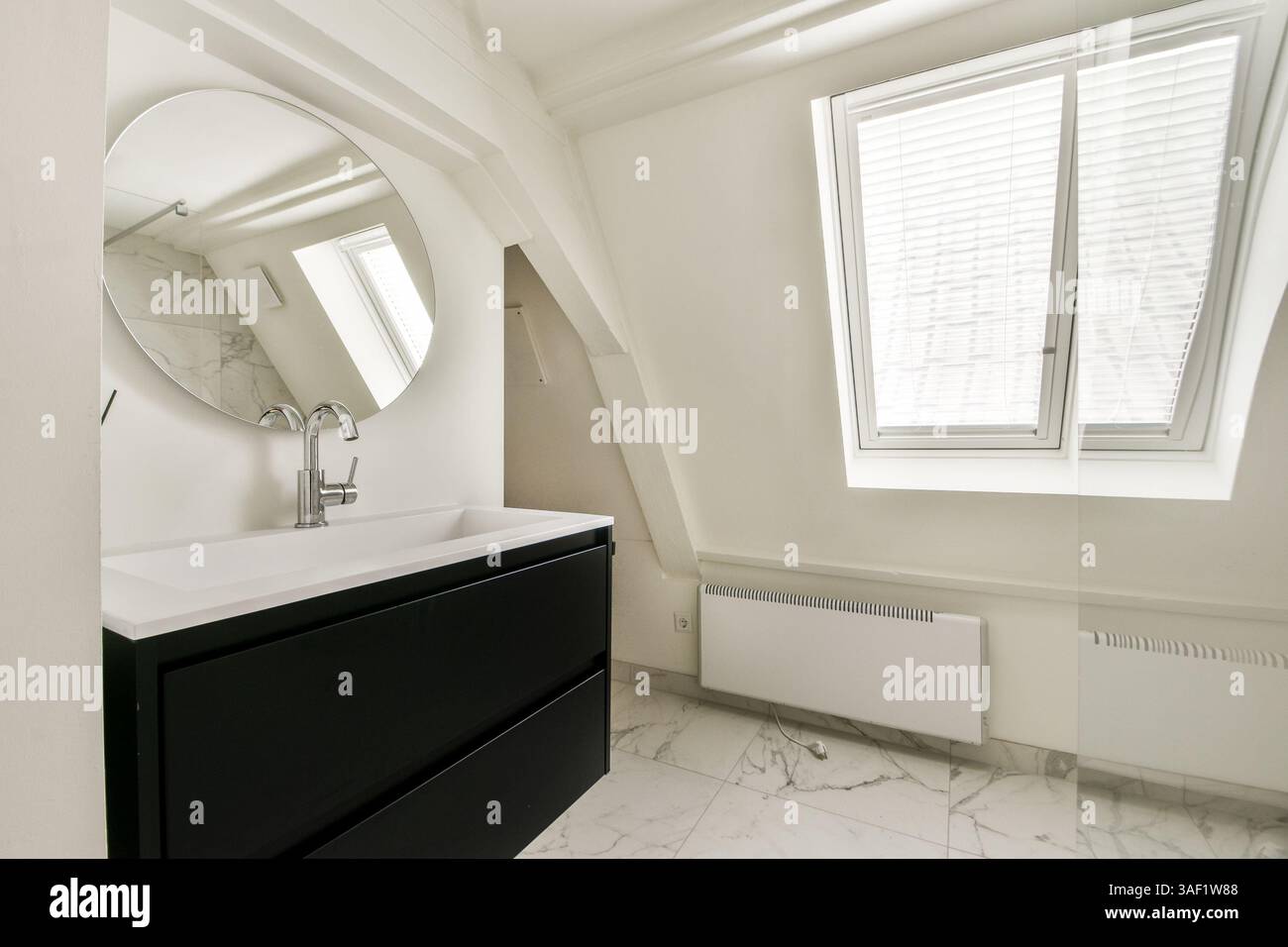 Un bagno elegante ed elegante con un elegante lavandino, specchio ed elementi di design minimalista con accenti in marmo. Foto Stock