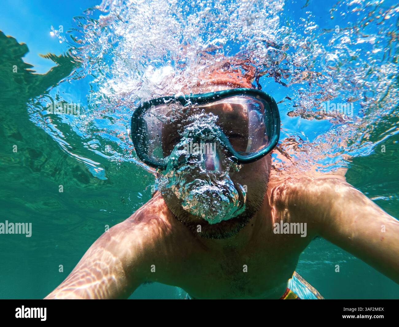 Uomo con maschera subacquea che nuota nell'oceano durante le vacanze estive, concentrazione selettiva Foto Stock