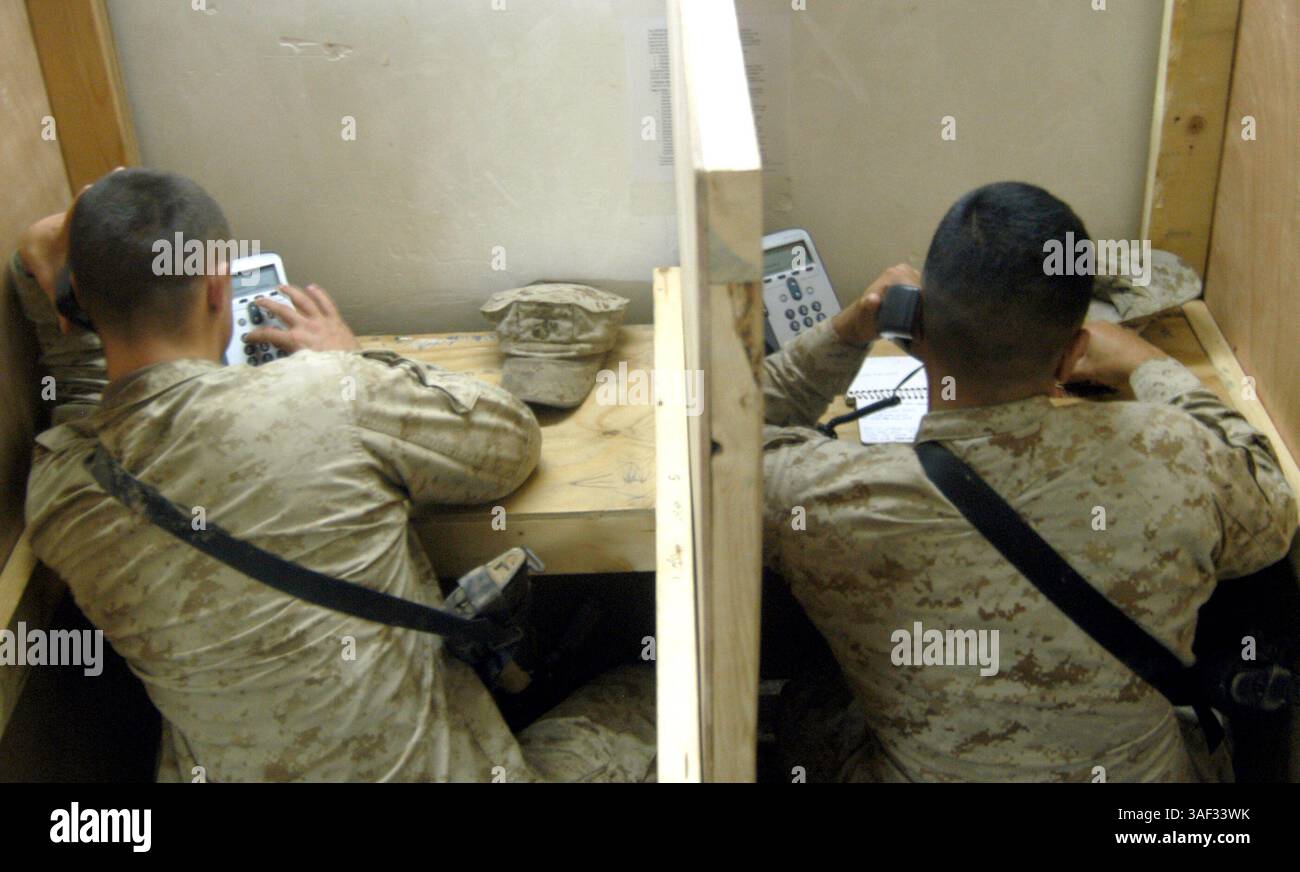 25 dicembre 2004; Camp Ramadi, Iraq; due Marines usano i telefoni per chiamare amici e famiglie a casa. Il giorno di Natale, i Marines e i marinai della batteria D'artiglieria, 2° Battaglione, 11° Reggimento Marines, 1° Divisione Marines, hanno avuto il giorno libero, per fare quello che volevano. Foto Stock