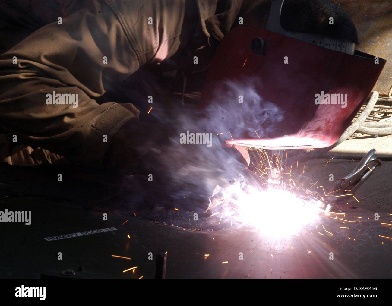 28 dicembre 2004; Camp Ramadi, Iraq; Cpl. GABRIEL CASILLAS, 2nd Battalion, 11th Marine Regiment, 1st Marine Division, un operatore di relitti tornato saldatore, salda un pezzo di metallo sulla parte superiore di una porta standard per una maggiore protezione per gli occupanti dell'humvee. Casillas è uno dei due caporale del 2nd Battalion, 11th Marine Regiment, 1st Marine Division che ha preso il lavoro di saldatura per il battaglione, anche se differisce dal loro lavoro ufficiale. Foto Stock