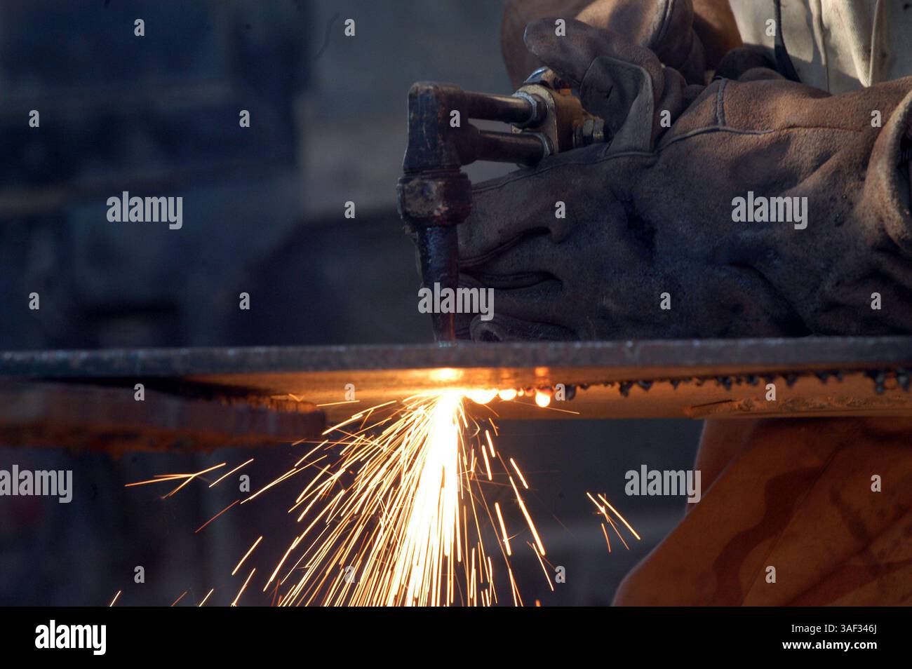 28 dicembre 2004; Camp Ramadi, Iraq; Mechanic Turned welder Cpl. BRONSON BARTLEY, 2nd Battalion, 11th Marine Regiment, 1st Marine Division taglia un pezzo di metallo che servirà come estensione per la porta. Bronson è uno dei due caporale del 2nd Battalion, 11th Marine Regiment, 1st Marine Division accetta il lavoro di saldatura per il battaglione, anche se differisce dal loro lavoro ufficiale. Foto Stock