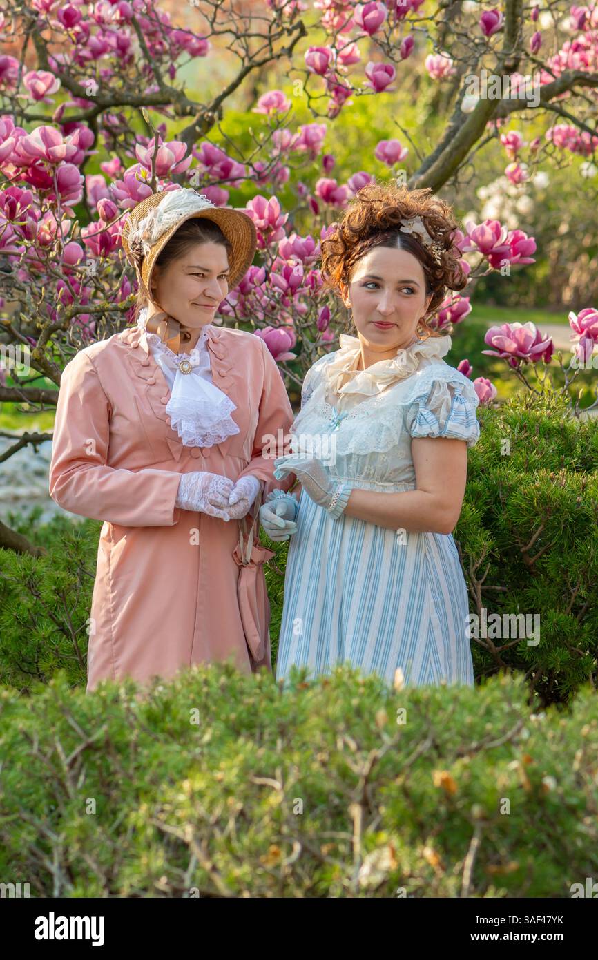 Donne in giardino in stile vittoriano che indossano guanti e cappelli in pizzo Foto Stock