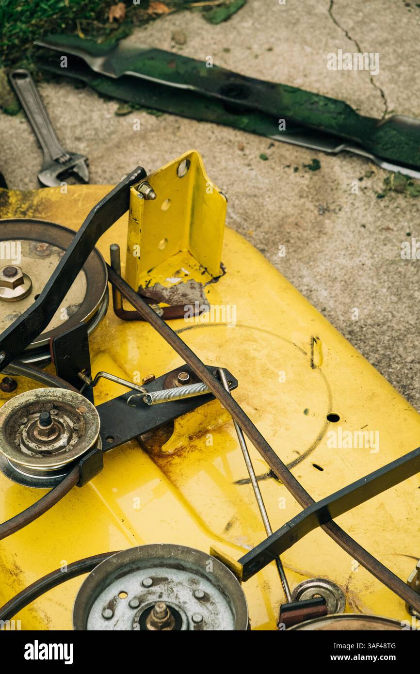 Componenti meccanici di un rasaerba lasciati esposti in un giardino Foto Stock