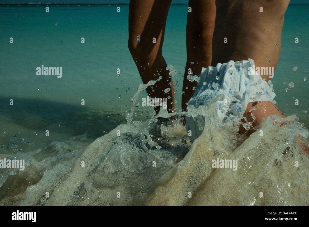 il bambino bagna le onde della spiaggia Foto Stock
