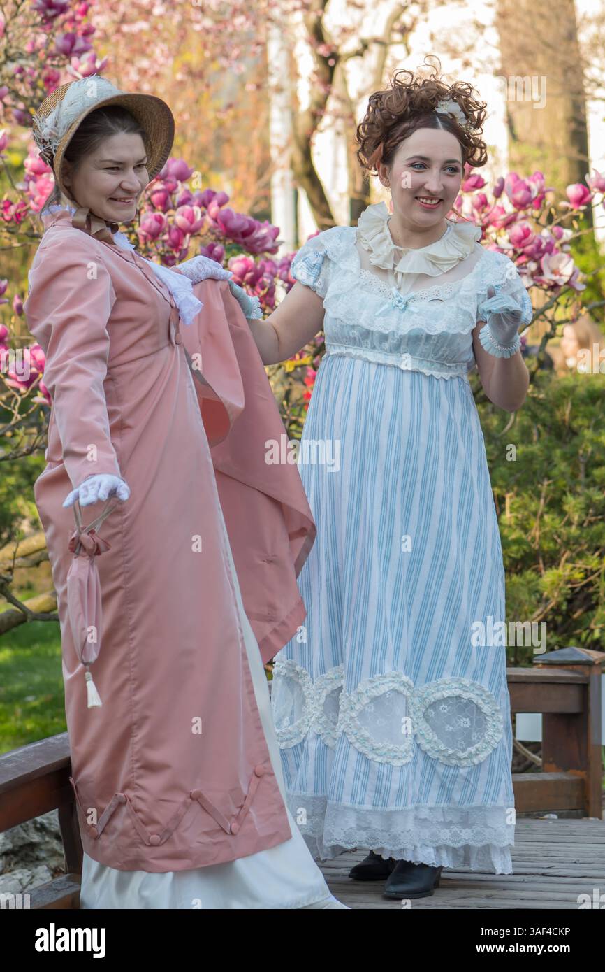 Una scena del passato - donne in abiti vintage sullo sfondo di alberi di magnolia in fiore Foto Stock