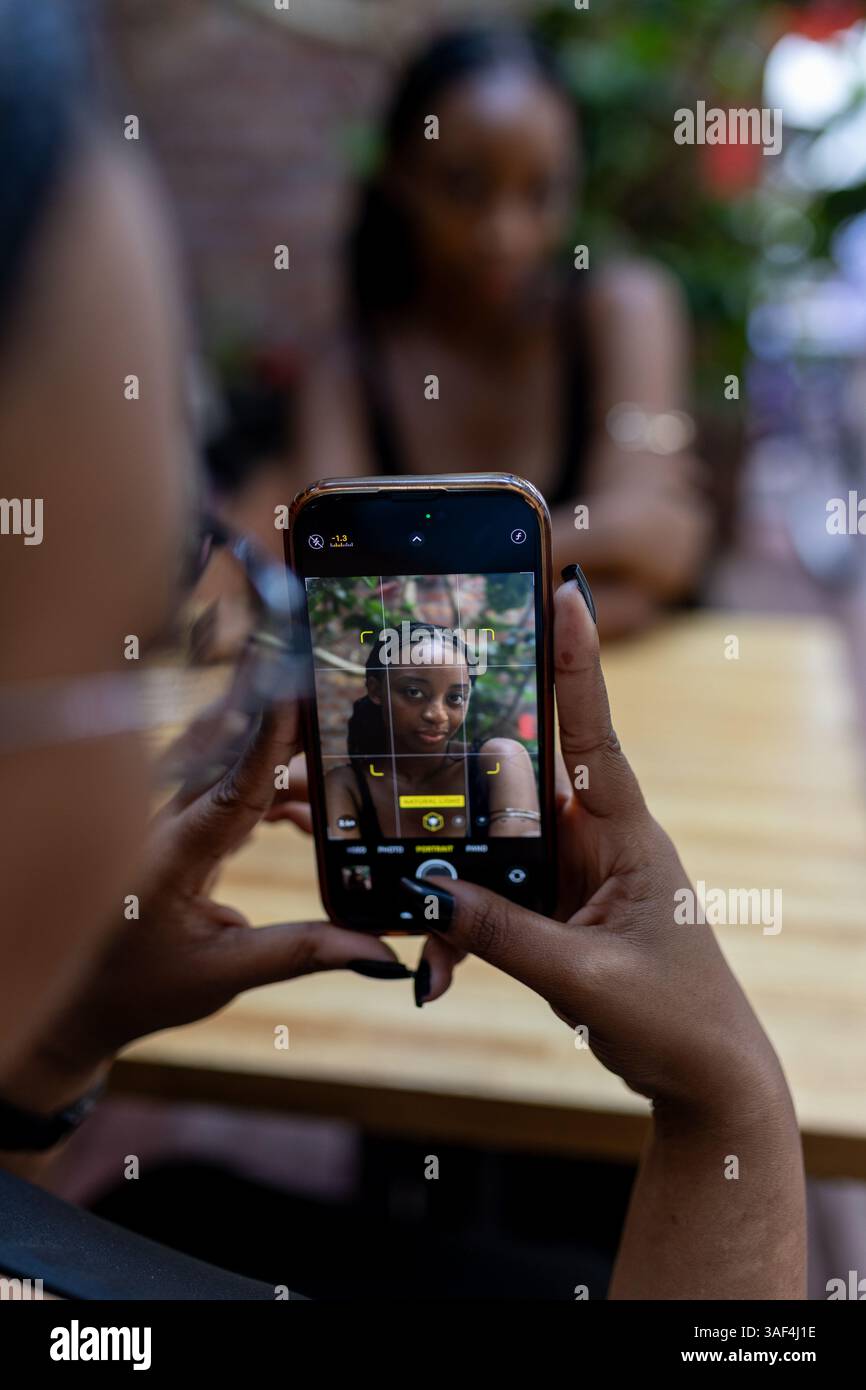 Una donna nera scatta una foto al cellulare Foto Stock