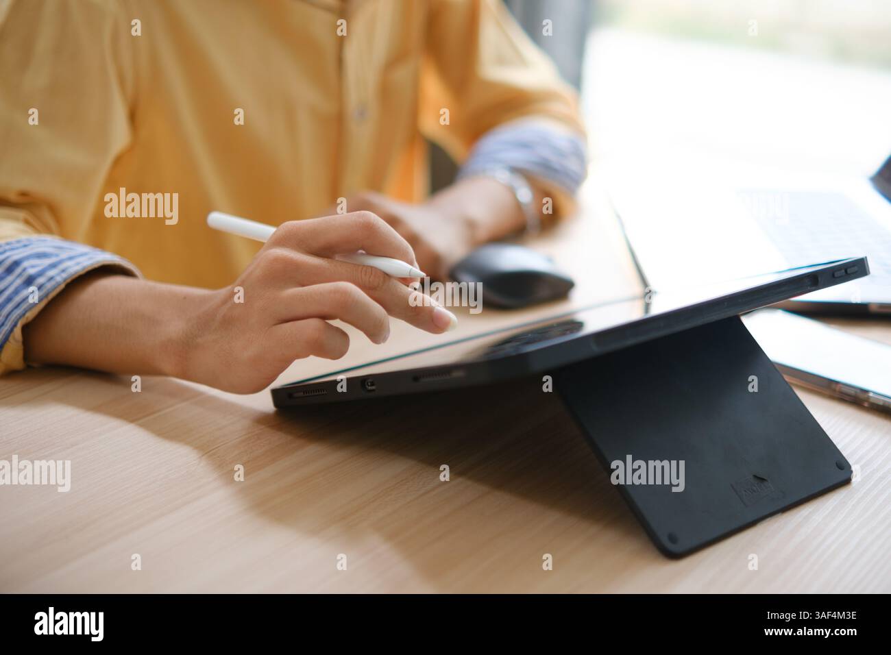 Web designer maschile che disegna con un tablet grafico al tavolo in ufficio. Foto Stock