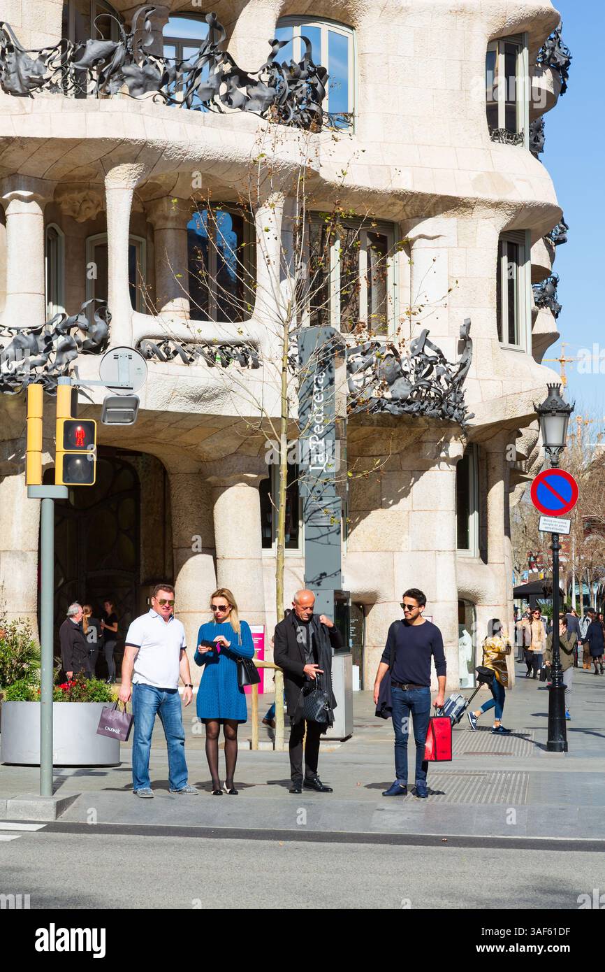 I turisti e la gente del posto aspettano un passaggio pedonale all'esterno dell'edificio la Pedrera progettato da Antoni Gaudí. Barcellona, Spagna Foto Stock