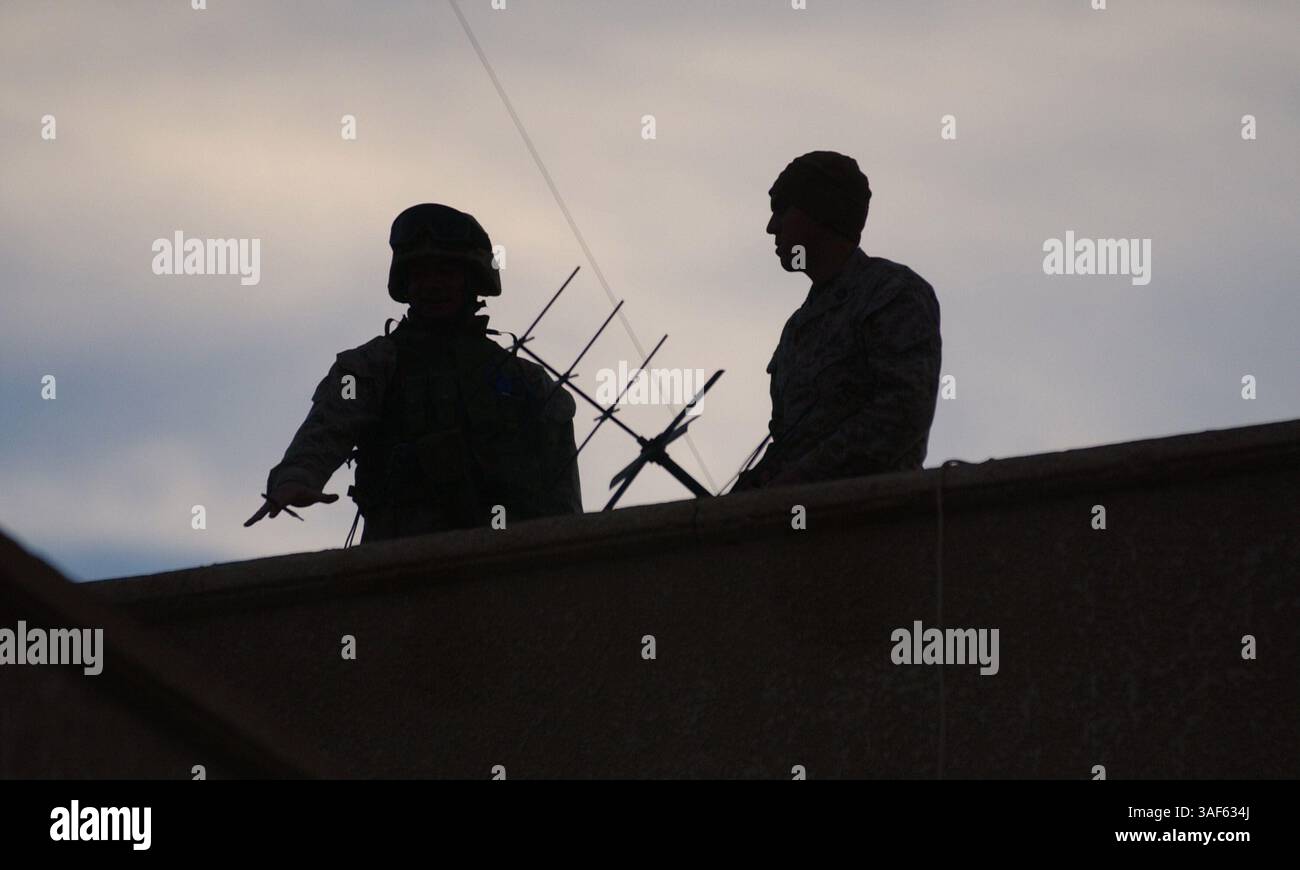 29 gennaio 2005; An Nukhayb, Iraq; due Marines della batteria G, 2nd Battalion, 11th Marine Regiment, osservano un edificio in An Nukhayb, Iraq gennaio 29. La batteria è designata come unità di artiglieria, tuttavia, è stata utilizzata come compagnia provvisoria di fucili da quando è stata dispiegata nell'operazione Iraqi Freedom lo scorso settembre. Da quando è stata dispiegata, la piccola unità ha completato oltre 450 missioni nella sua area operativa. Foto Stock