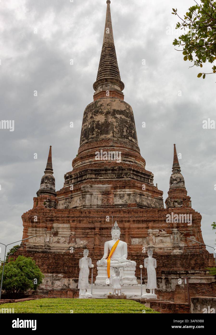 Edificio in mattoni rossi e templi in pietra in rovina e statua di buddha in oro del parco storico Wat Yai Chai Mongkhon ad Ayutthaya in Thailandia Foto Stock