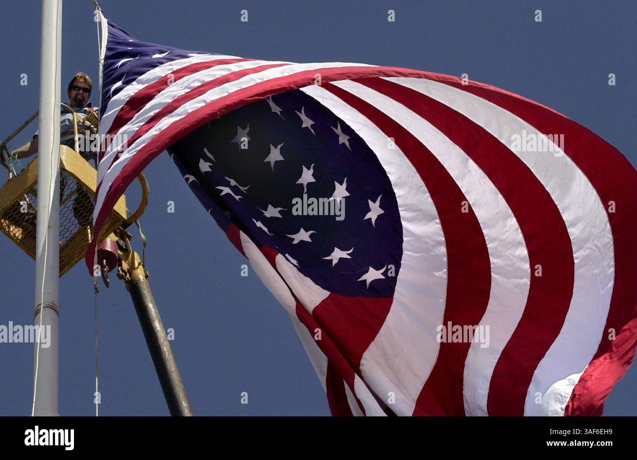 Tommy Gray (CQ), un dipendente della Pacific Neon Co., si trovava in una selezionatrice di ciliegi in cima a un'asta di bandiera di 110 piedi per aiutare a svelare un gigantesco 20 piedi. x 30 piedi Bandiera americana presso gli uffici della Pacific Neon Co visibile dalla Business 80 vicino ad Arden Way venerdì 14 settembre 2001, in questo spettacolo di patriottismo. Le bandiere stanno sventolando in tutto il paese e molte auto e camion che passavano in autostrada hanno suonato il corno in supporto mentre vedevano la bandiera gigante salire nel cielo. La bandiera, una volta sventolata, fu messa a metà del personale. (Sacramento Bee/Chris Crewell) /ZUMA Press Foto Stock