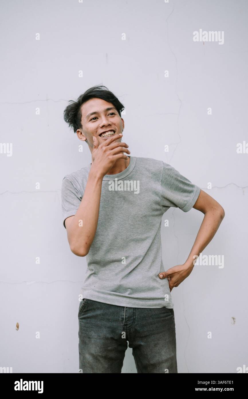 Giovane felice in abiti casual che guarda in alto e sorride. Ritratto di un uomo sorridente che pensa a qualcosa di positivo. Foto Stock