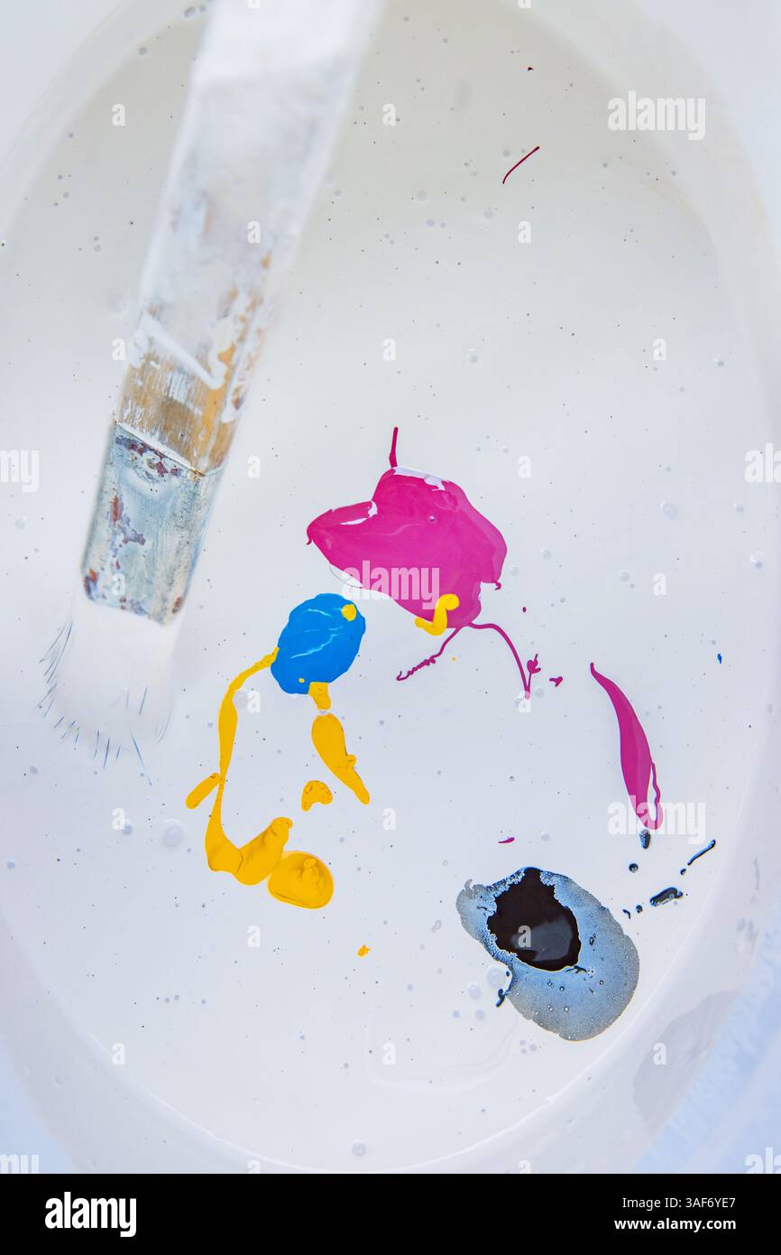 Mescolare i colori di vernice con il pennello per dipingere le pareti dell'appartamento. Il lavoratore del pittore mescolare le vernici nel secchio con il pennello. Camera reno Foto Stock