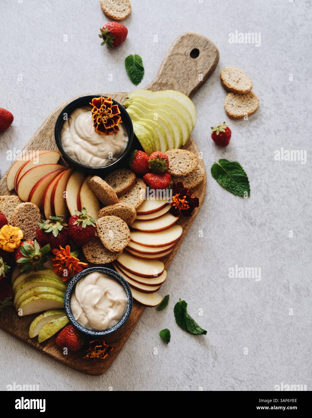 top shot, piano di un asse di legno con diversi tipi di frutta a fette, toast e salsa color crema Foto Stock