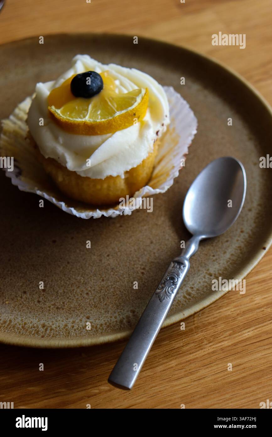 Cupcake al limone su un piatto di portata marrone con cucchiaio vintage Foto Stock