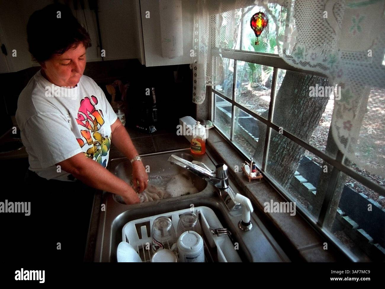 Ci.104904.- - CONSEGNA A:.Citrus.- -.5/30/2000..Homosassa.DIDASCALIA INFO:. Connie Byrd lava i suoi piatti veloci nel suo lavandino. Stima di usare circa un litro d'acqua al giorno per lavare i piatti di Breckfast, pranzo e cena. GENERALE: Richard e Connie Byrd vivono su un'isola sul fiume Homosassa. Devono risparmiare ogni goccia d'acqua possibile durante tutto l'anno. Si stima che utilizzino in media 30 galloni di acqua al giorno. Ciò include cucina, servizio sveglia, doccia, pulizia e giardinaggio. La maggior parte della loro acqua proviene dalle cisterne dietro casa loro. L'acqua del bagno viene pompata dal riv Foto Stock