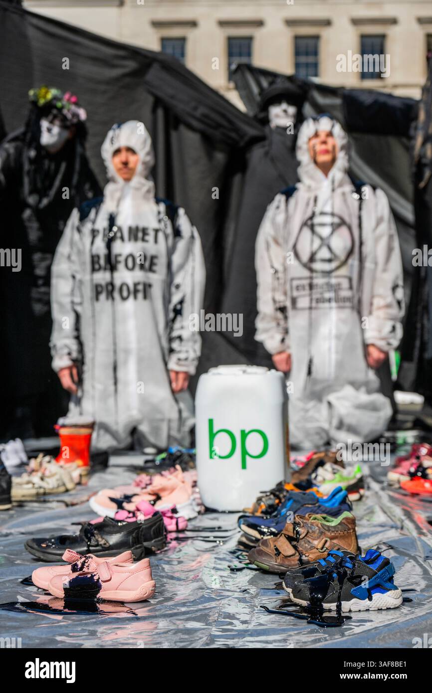 Londra, Regno Unito. 7 aprile 2025. Un manifestante vestito da dirigente della BP, e supportato da petroliere in vesti nere, versava olio su ribelli inginocchiati, e poi su file di scarpe vuote per bambini davanti all'edificio, simboleggiando ciò che la strategia della BP a U significa per il futuro dei nostri figli. Gli attivisti di età compresa tra i 4 e i 83 anni hanno occupato la strada fuori dal quartier generale di Londra di St James's Square della BP per chiedere al gigante petrolifero di invertire la loro decisione di rottamare la precedente strategia di transizione energetica sostenuta dagli azionisti. Il volto del CEO, Auchincloss, è apparso sui cartelli che recitano: "RICERCATO per distruggere i nostri Futures". Credito Bell/Alamy Foto Stock