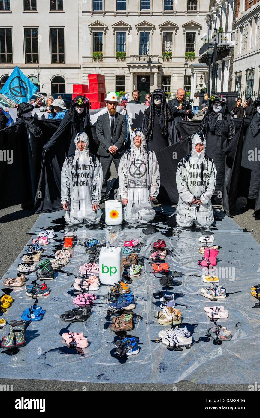 Londra, Regno Unito. 7 aprile 2025. Un manifestante vestito da dirigente della BP, e supportato da petroliere in vesti nere, versava olio su ribelli inginocchiati, e poi su file di scarpe vuote per bambini davanti all'edificio, simboleggiando ciò che la strategia della BP a U significa per il futuro dei nostri figli. Gli attivisti di età compresa tra i 4 e i 83 anni hanno occupato la strada fuori dal quartier generale di Londra di St James's Square della BP per chiedere al gigante petrolifero di invertire la loro decisione di rottamare la precedente strategia di transizione energetica sostenuta dagli azionisti. Il volto del CEO, Auchincloss, è apparso sui cartelli che recitano: "RICERCATO per distruggere i nostri Futures". Credito Bell/Alamy Foto Stock
