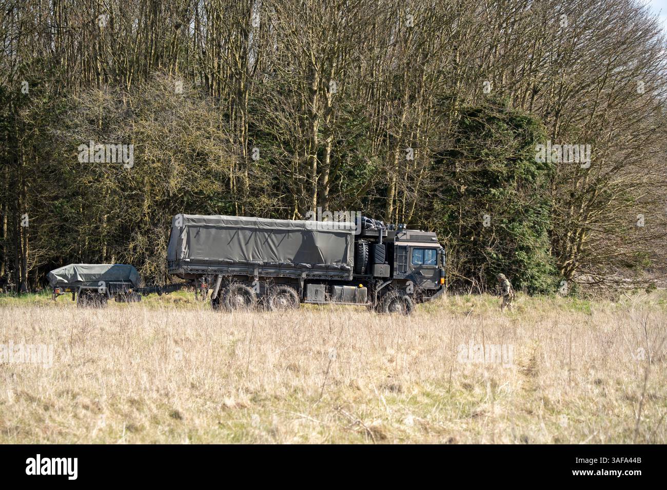 Camion multiuso MAN HX 6x6 dell'esercito britannico con rimorchio in movimento lungo una pista sterrata in campagna Foto Stock