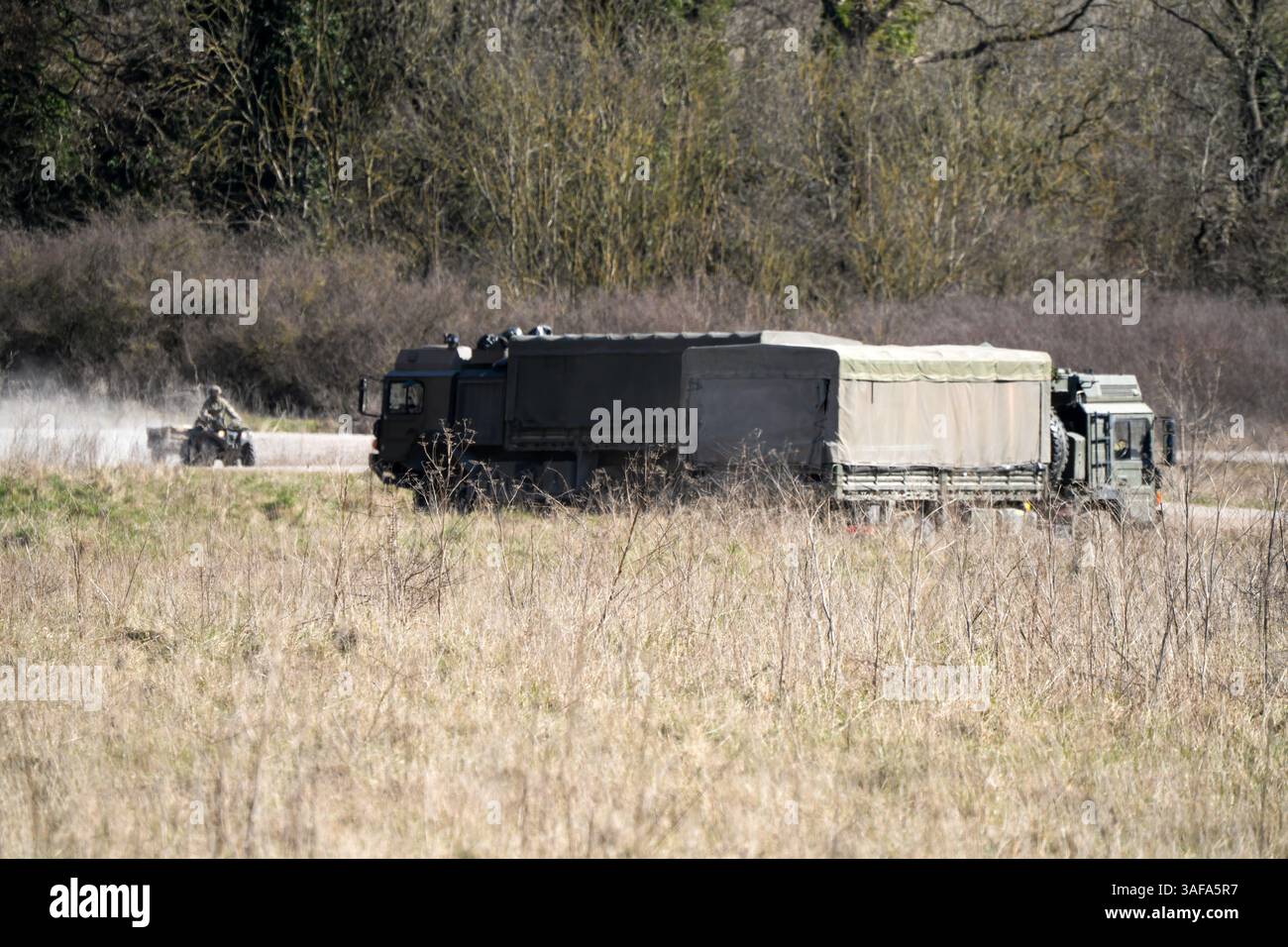 Camion multiuso MAN HX 6x6 dell'esercito britannico con rimorchio in movimento lungo una pista sterrata in campagna Foto Stock