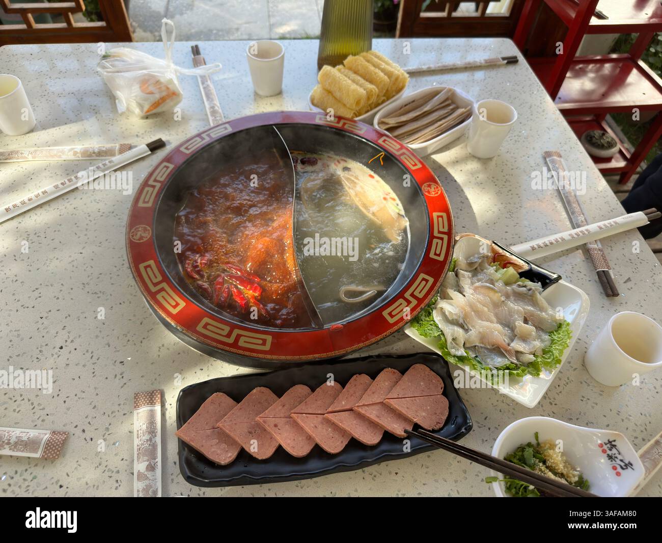 Un tavolo per un pasto hot pot cinese in Cina caratterizzato da vari ingredienti e un delizioso ambiente. Foto Stock