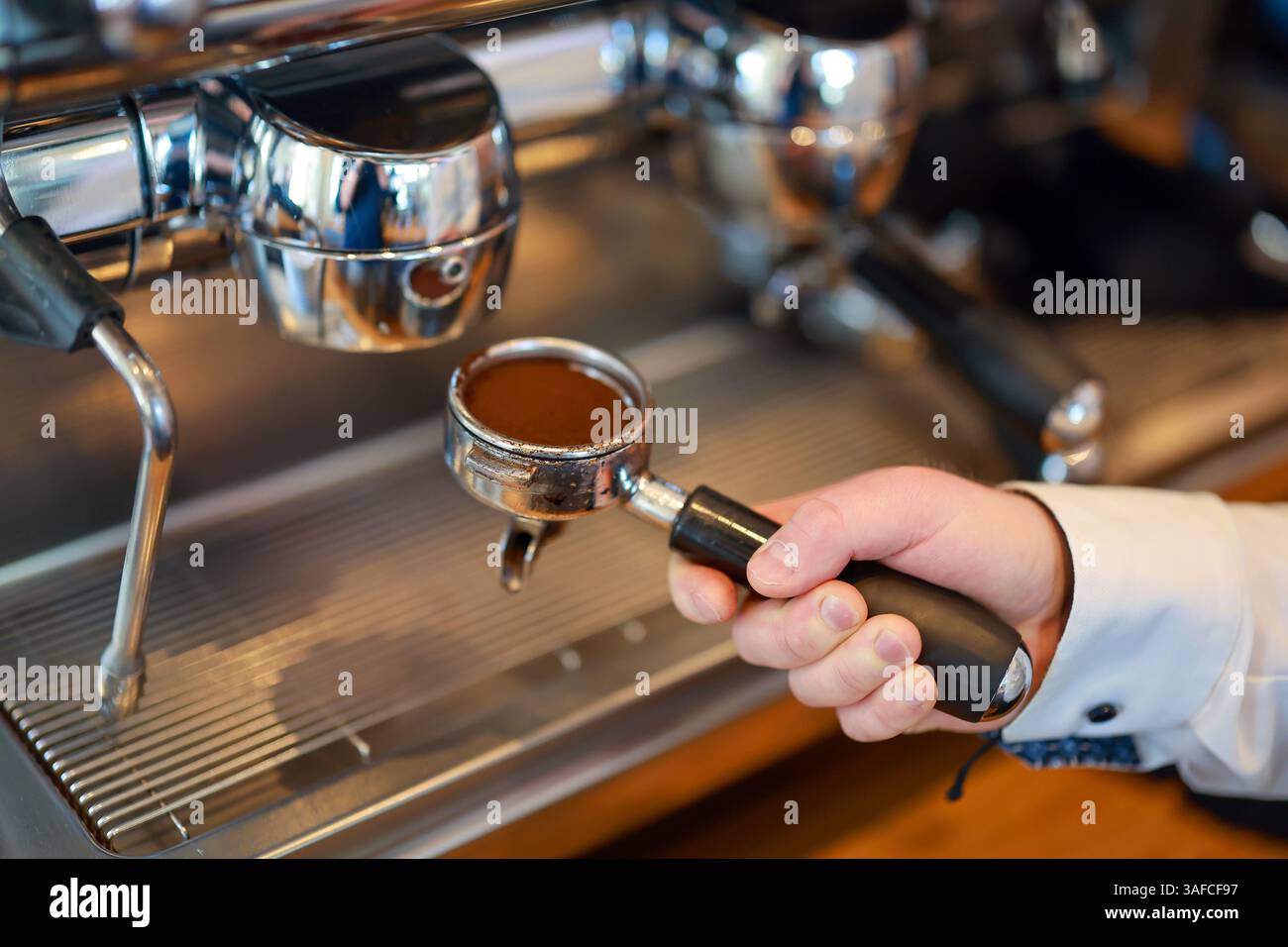 Germania - il barista prepara un caffè, trasporta a mano un setaccio riempito di polvere di caffè nella macchina per il caffè. Foto Stock