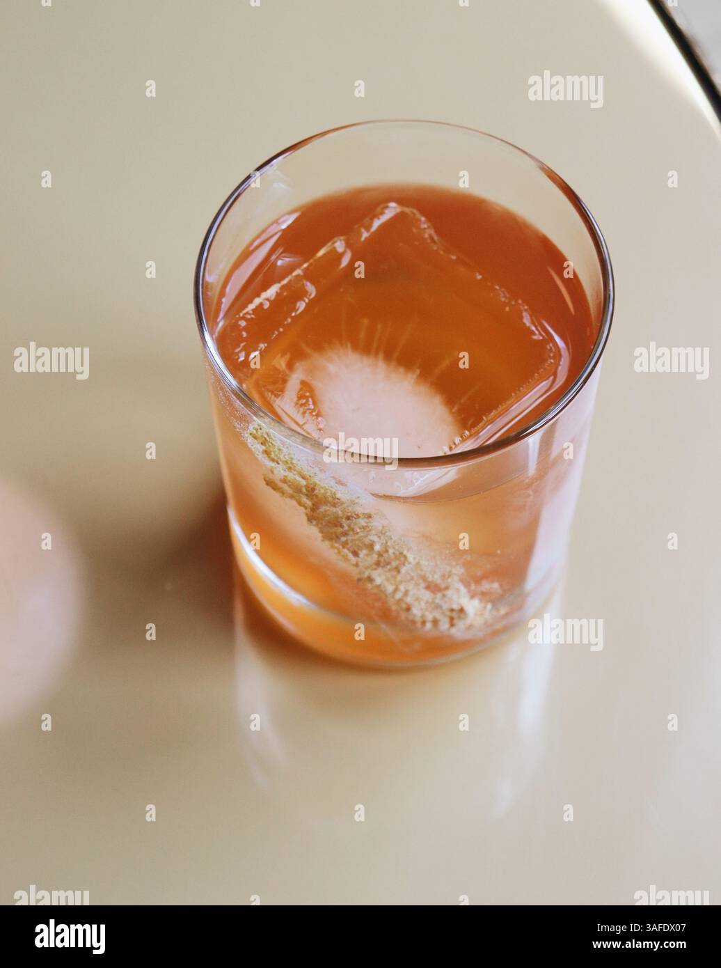 Elegante cocktail arancione trasparente su un bicchiere corto con grande cubetto di ghiaccio e guarnire lateralmente Foto Stock Elegante cocktail arancione trasparente su un bicchiere corto con grande cubetto di ghiaccio e guarnire lateralmente Foto Stock