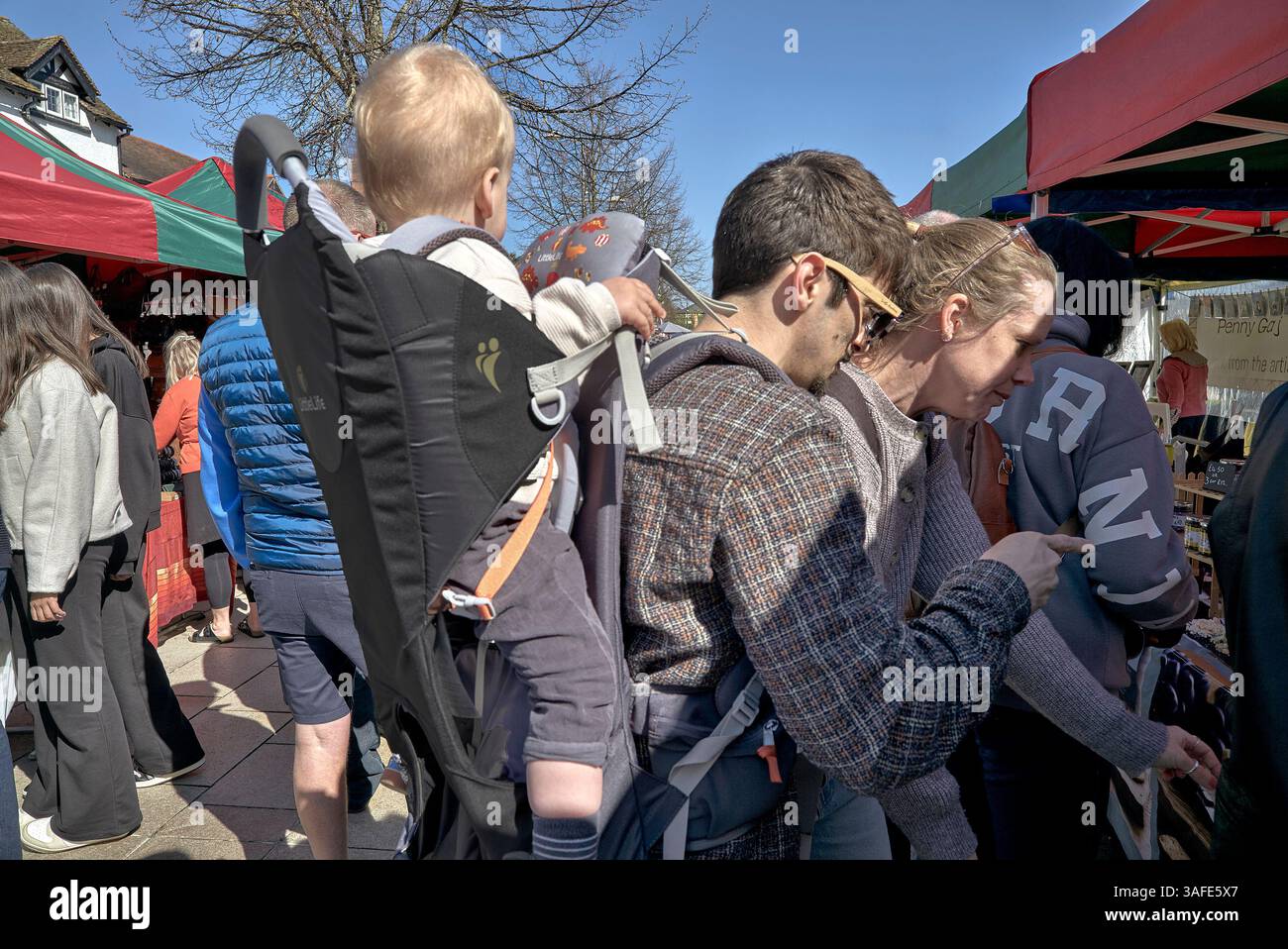 Padre che porta il bambino in uno zaino portabicchieri mentre fa shopping in un mercato di strada. Inghilterra, Regno Unito Foto Stock