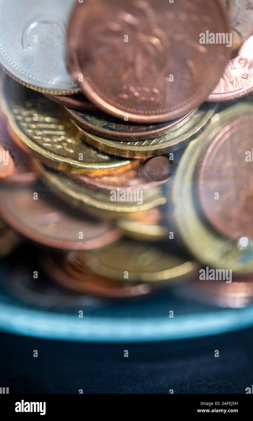 Monete di diverse valute raccolte in un vaso di vetro Foto Stock
