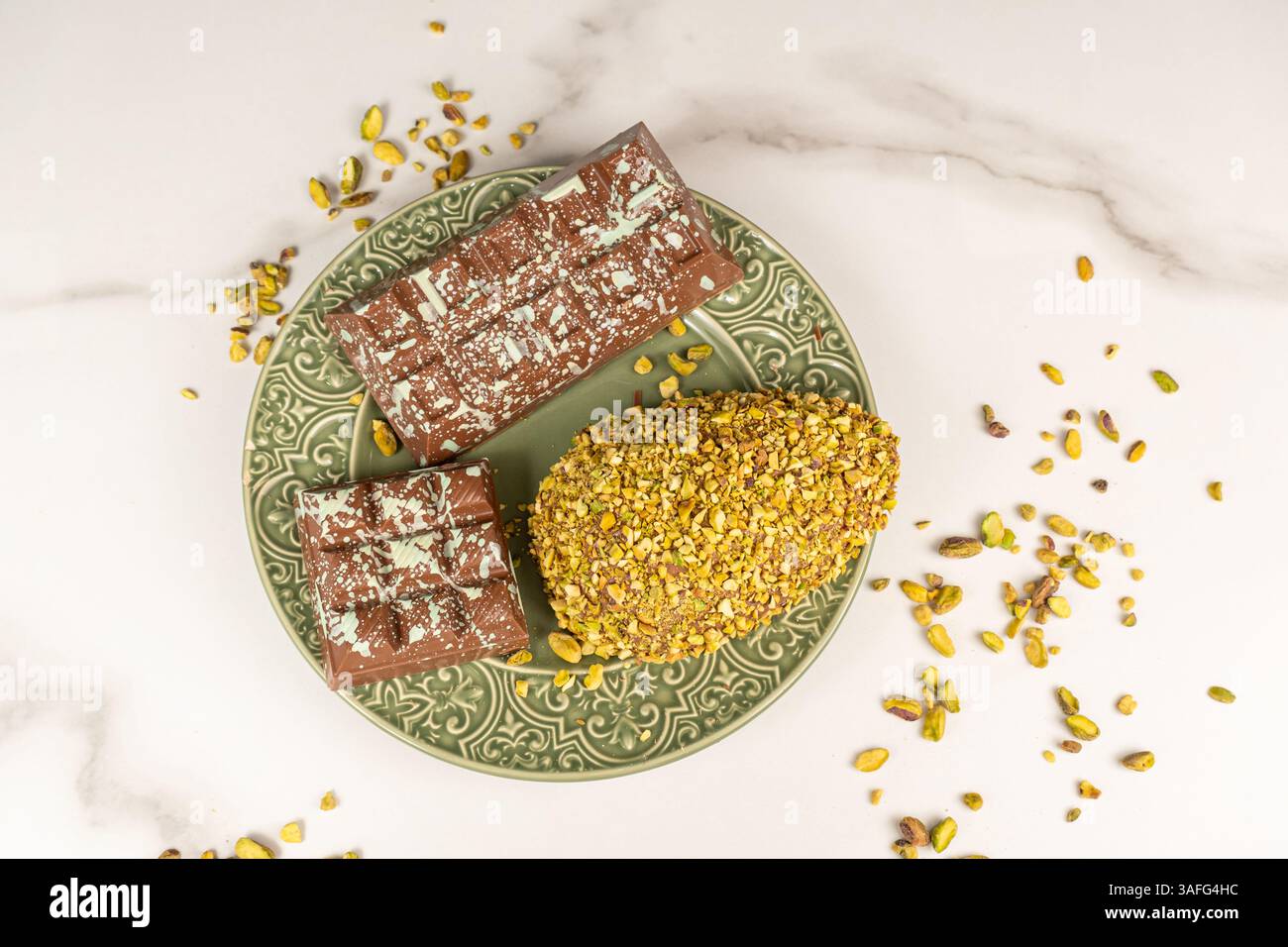 Uovo di Pasqua con pezzi di pistacchio e barretta di cioccolato vista dall'alto. Foto Stock
