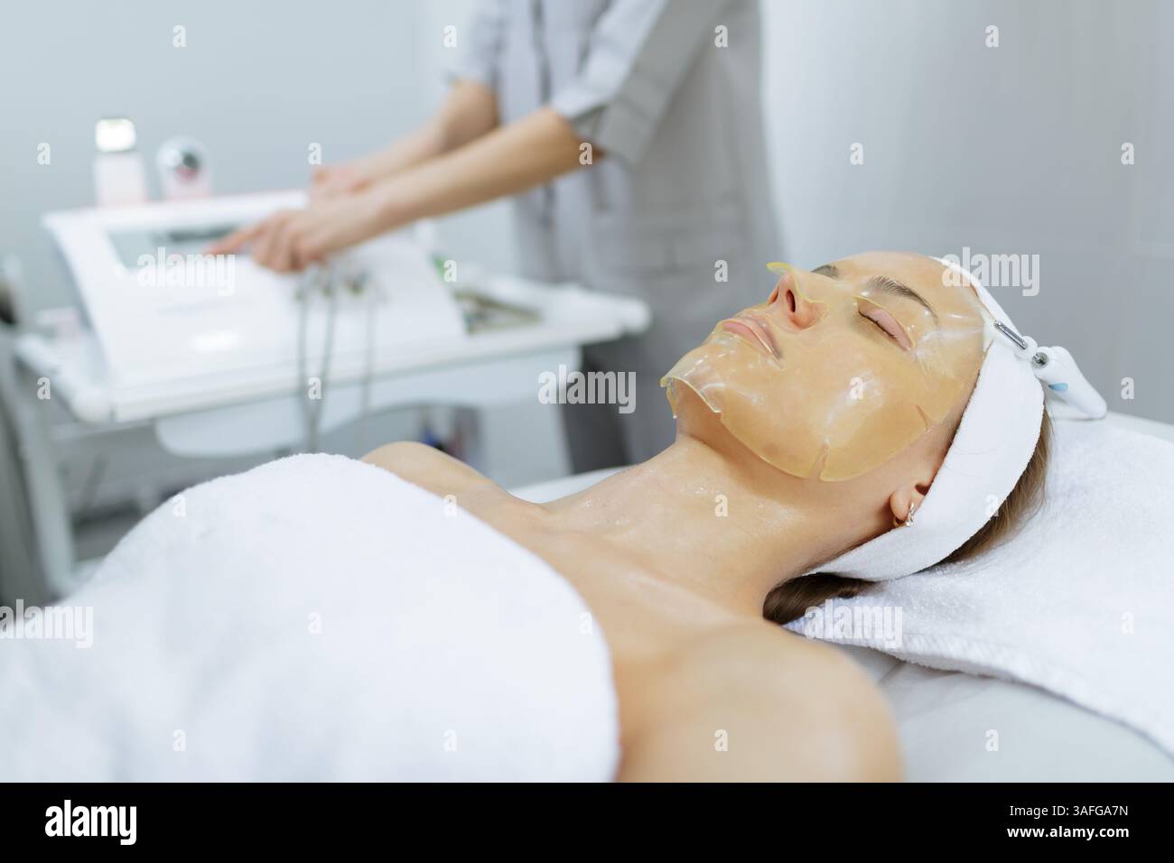 Donna che riceve un trattamento maschera viso ringiovanente in un salone di bellezza professionale per l'idratazione della pelle. Foto Stock