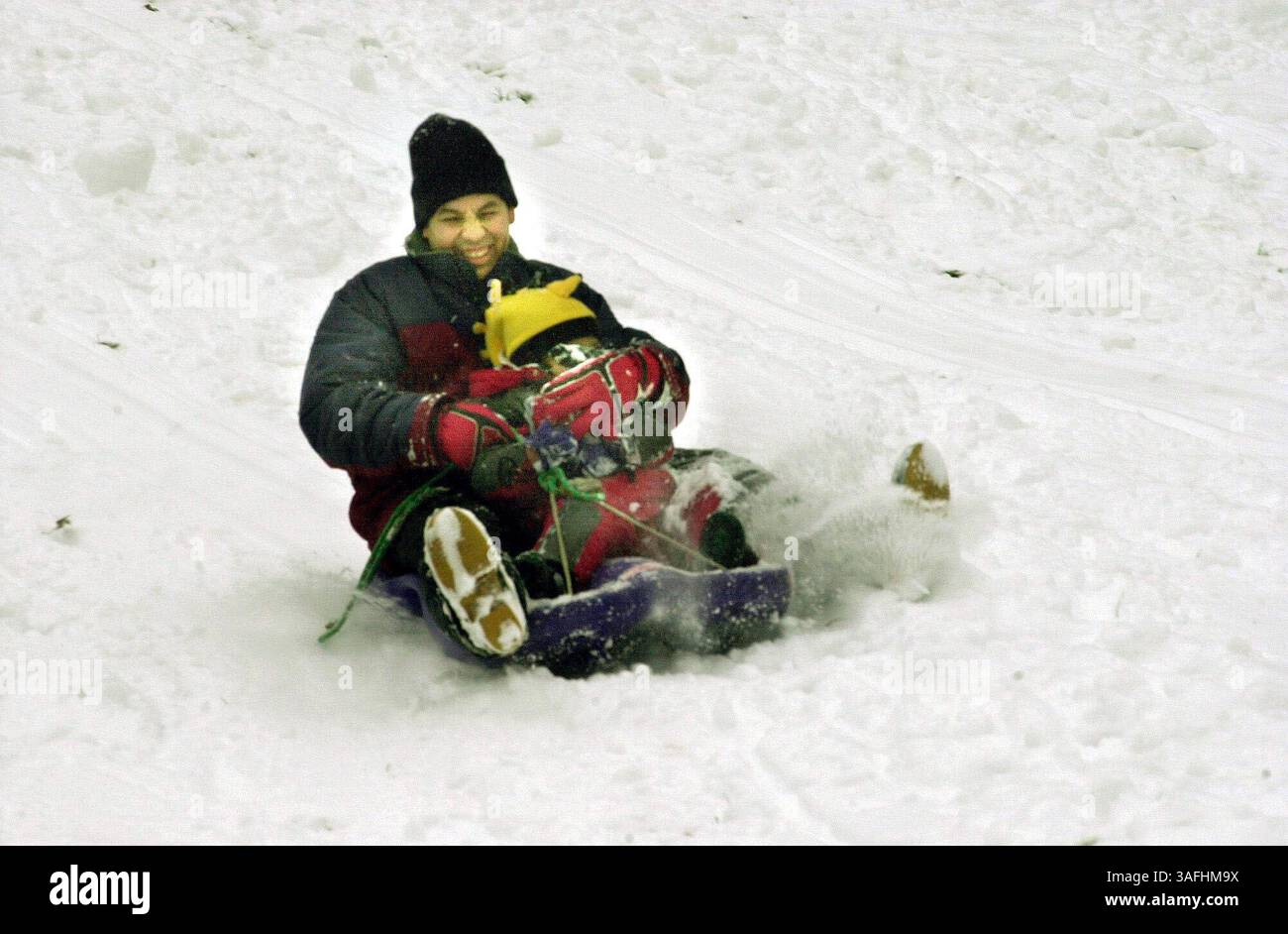 Ferando Estrada protegge suo figlio Luis, 3 anni, mentre scivolano giù dalla collina sulla loro slitta a Ridgeview Park nella contea di Fairfax giovedì mattina 5 dicembre 2002, durante la prima nevicata della stagione nell'area di Washington. (Immagine di credito: The Washington Times/ZUMAPRESS.com) Foto Stock