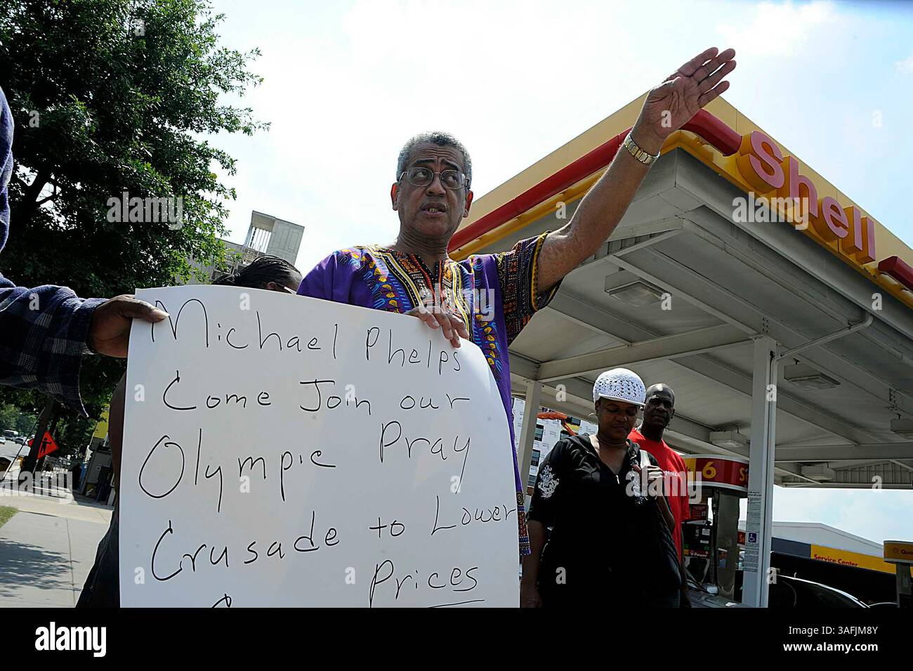 Rocky Twyman, che ha iniziato la preghiera al movimento Pump diversi mesi fa, è venuto alla stazione Shell di Upshur e Georgia Ave. NW con i sostenitori mercoledì 13 agosto 2008 per ringraziare Dio per i prezzi del gas più bassi. Qui regge un cartello che invita anche il nuotatore olimpico Michael Phelps a unirsi al movimento. Il signor Twyman sta pregando per abbassare i prezzi del gas, e dice che il suo movimento sta funzionando e ha raccolto circa 300 sostenitori in tutta la nazione. Evidentemente Jay Leno ha sentito parlare del movimento e lo ha deriso nel suo show alla fine di luglio, quindi ora il signor Twyman sta invitando il signor Leno a venire a pregare con h Foto Stock