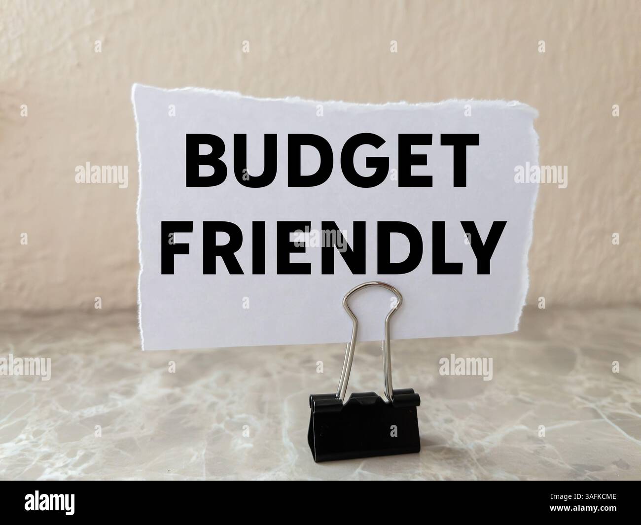 Messaggio economico scritto su un pezzo di carta bianca strappato sullo sfondo della parete. Simbolo di budget concettuale. Copia spazio. Foto Stock