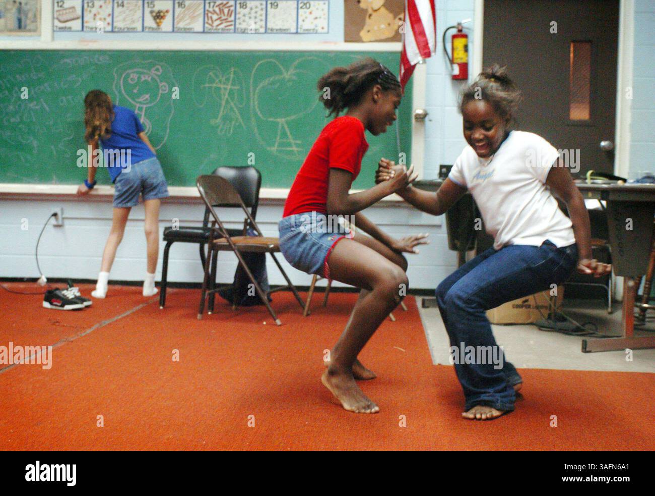 Carol Carozza, 10 anni, disegna sulla lavagna, mentre Keke King, 11 anni e Meme Etienne, 9 anni, ballano alla scuola Booker T. Washington su Pine Hill Road a Port Richey giovedì sera 14 gennaio 05. Un gruppo di bambini stava praticando una danza per la celebrazione del Martin Luther King Day di lunedì al Sims Park di New Port Richey. Questa è la prima volta che l'evento si tiene dal 2001 a causa del scarso sostegno della comunità e di un budget limitato. Bambini e volontari si incontrano tre giorni alla settimana nella scuola di Pine Hill Road a Port Richey per aiutare con il lavoro scolastico, i giochi e altre attività. (Immagine di credito: St Petersburg Times/ZU Foto Stock