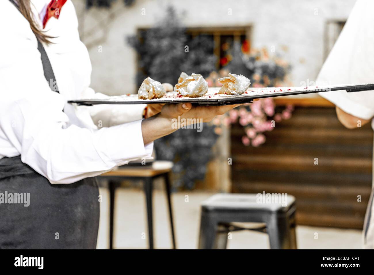 Cameriera con arco rosso che offre tartine o stuzzichini su un vassoio durante un matrimonio o un evento Foto Stock